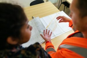 Home Two engineers reviewing construction blueprints on a table in an office setting.