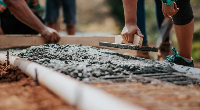 pexels photo 2219024 2219024 1 Construction workers leveling fresh cement on a sunny day at an outdoor site.
