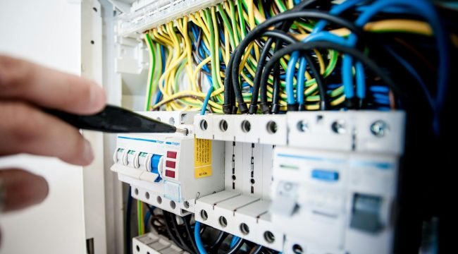 pexels photo 257736 257736 Hand of electrician working on a circuit breaker panel with colorful wires, ensuring safe electrical connections.